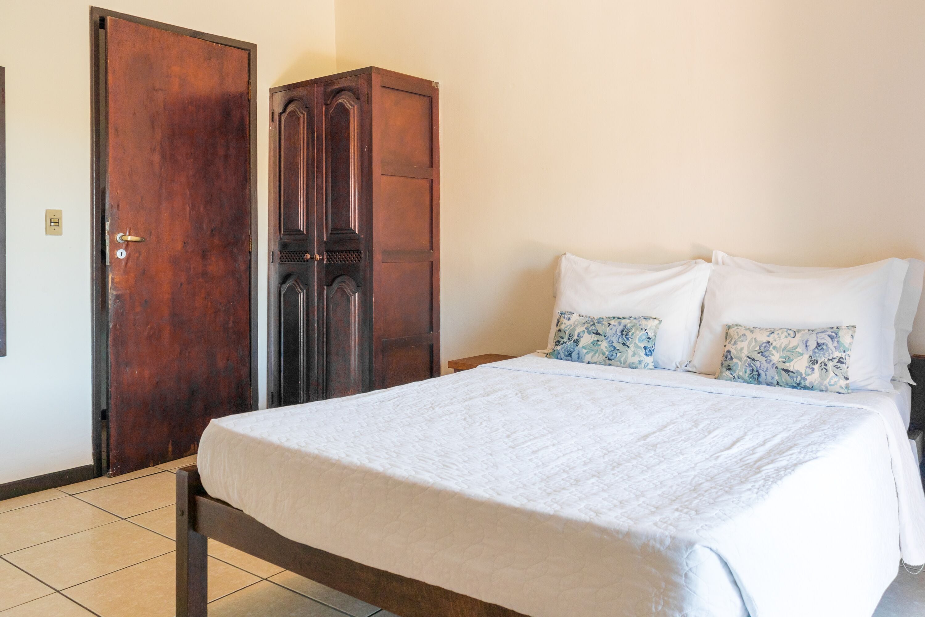 A bedroom with a bed, a wardrobe, and a door.