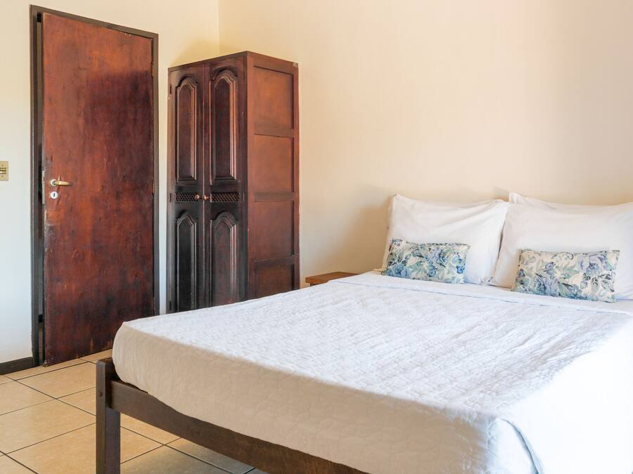 A bedroom with a bed, a wardrobe, and a door.