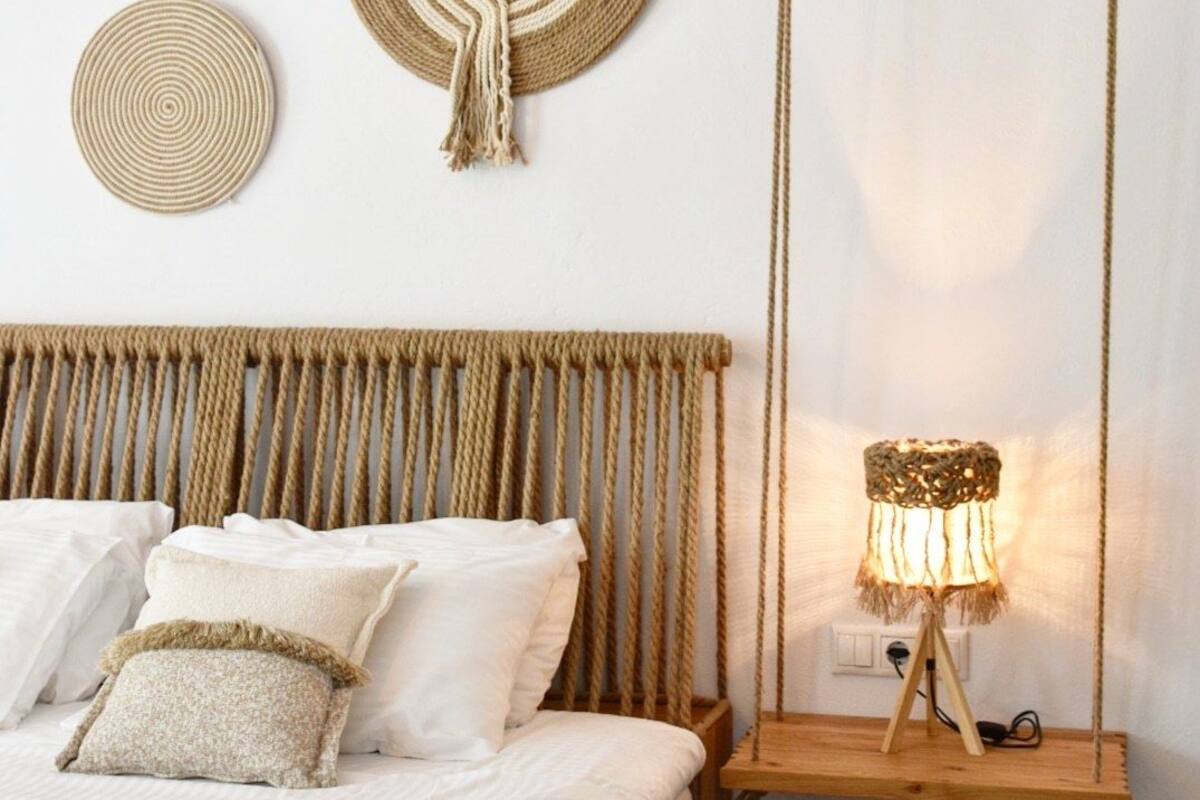 A bedroom with a bed, a hanging swing, and two woven wall decorations.