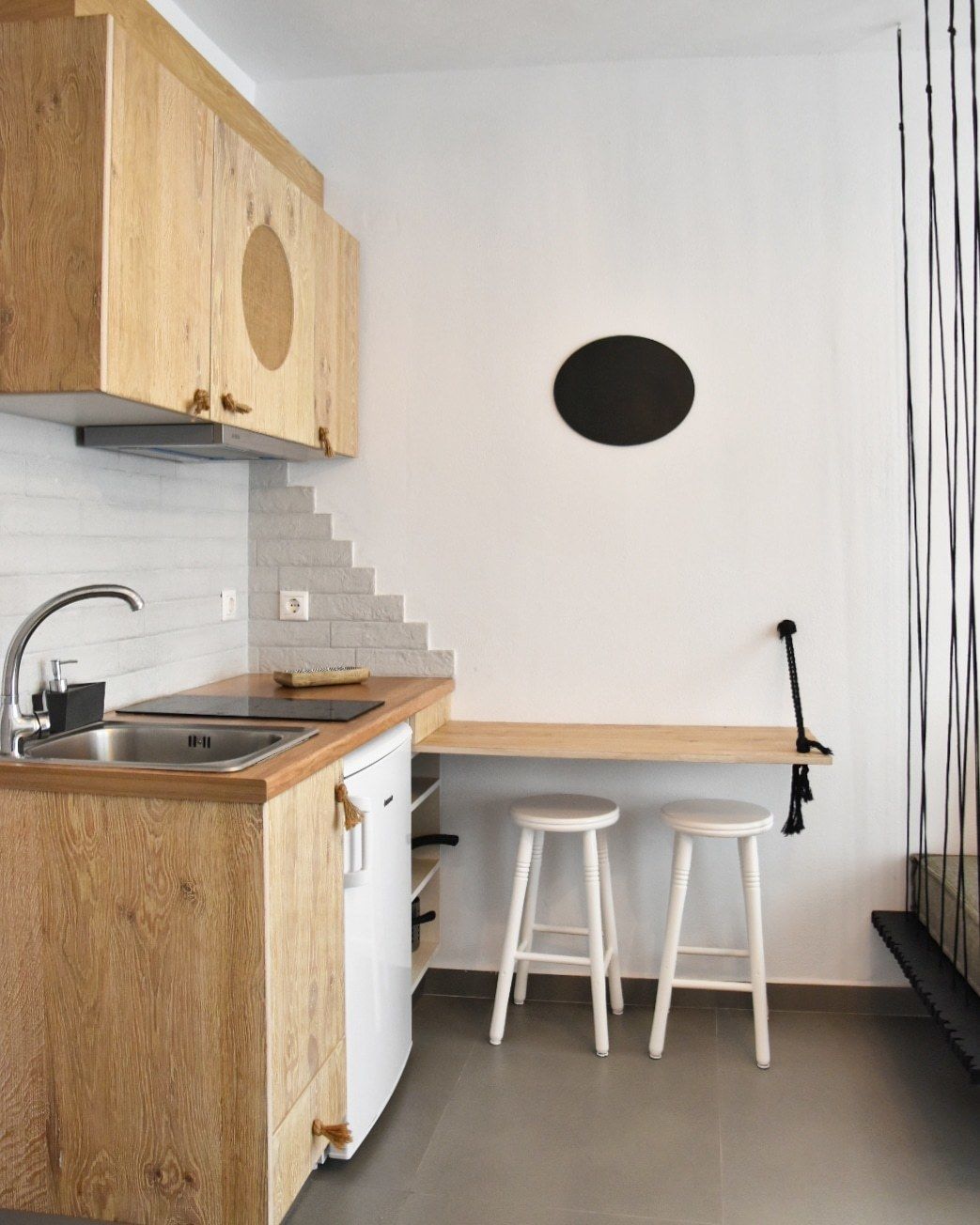 A modern kitchen with wooden cabinets, a stainless steel sink, and a white countertop.