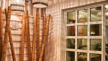 A room with bamboo decor, a window with multiple panes, and a small stool with a plant.