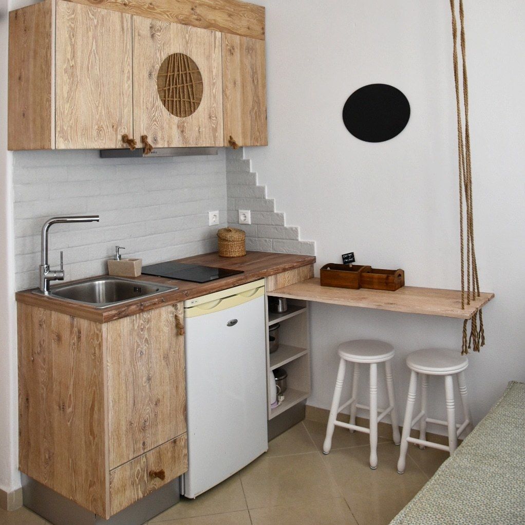 Cocina compacta con muebles de madera, lavavajillas integrado, un lavabo y una pequeña barra con taburetes.