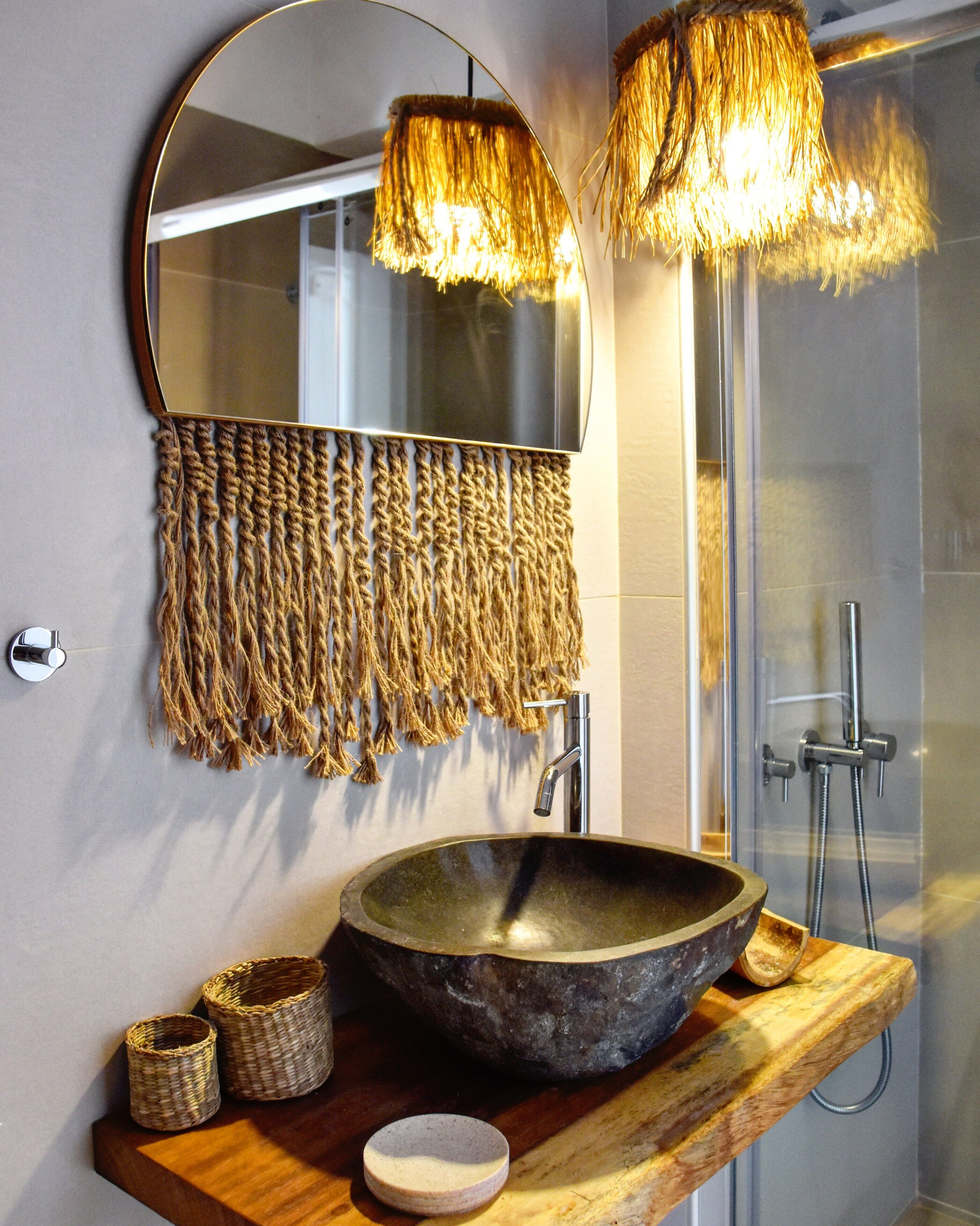 A bathroom with a large mirror, a stone sink, and a shower.