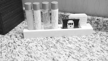 A bathroom vanity with a marble countertop, a white soap dispenser holder, and a small black and white photo of a train.