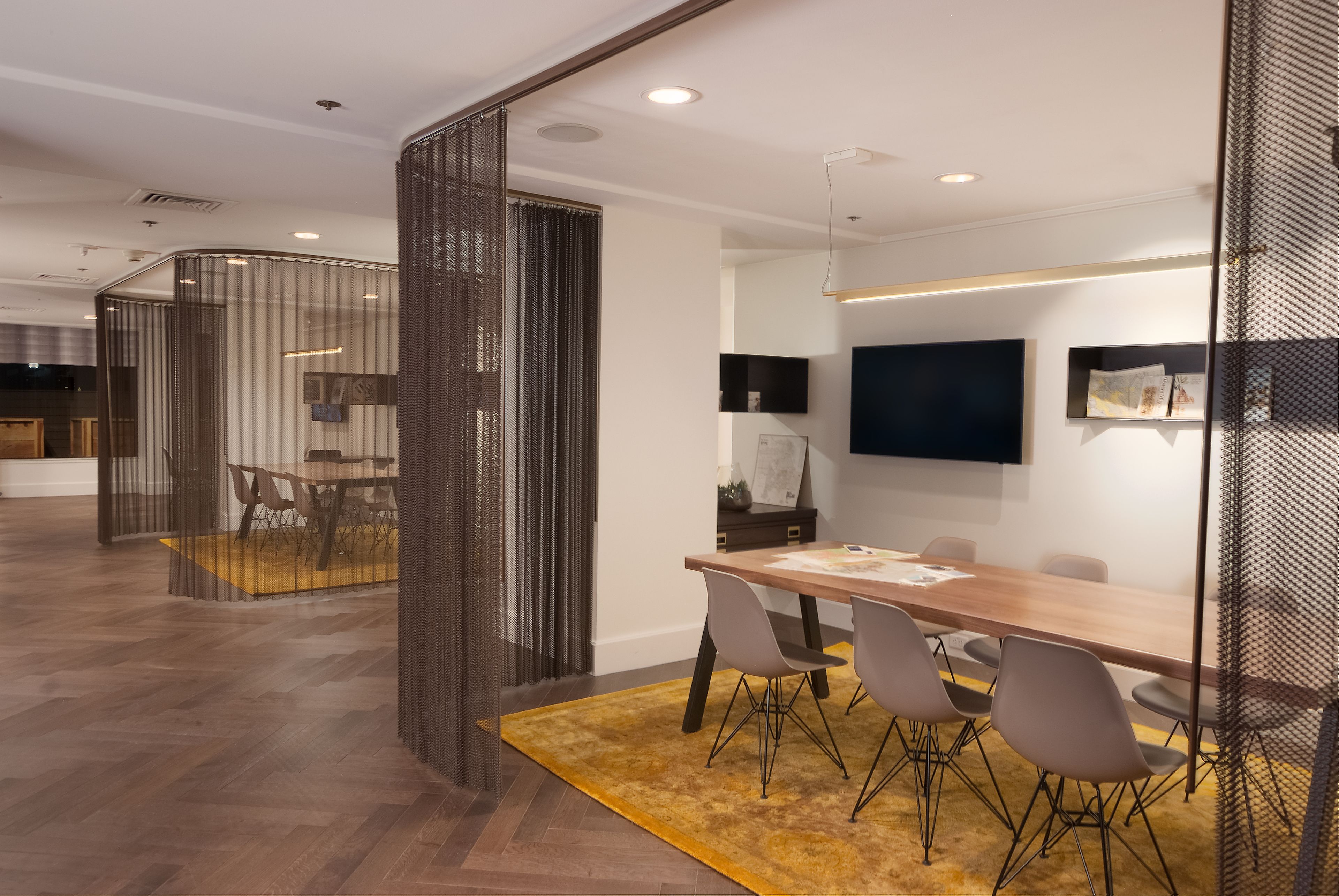 A modern conference room with a long table, chairs, and a yellow rug.
