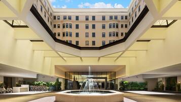 Experience the serene atmosphere of our atrium, featuring a central fountain and lush greenery, surrounded by a spacious and symmetrical design.