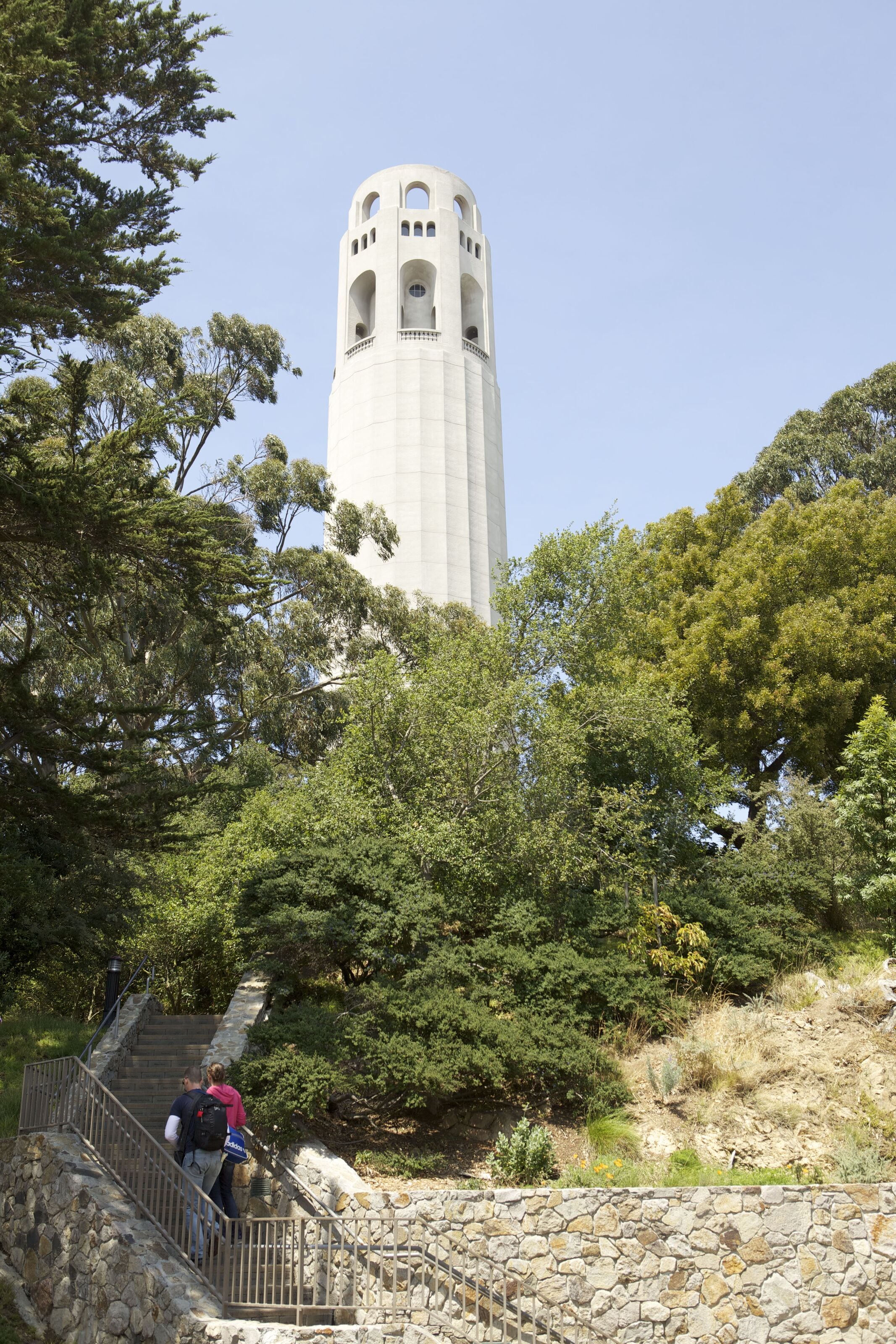 A stone staircase leading to a tower with arched windows, surrounded by trees.