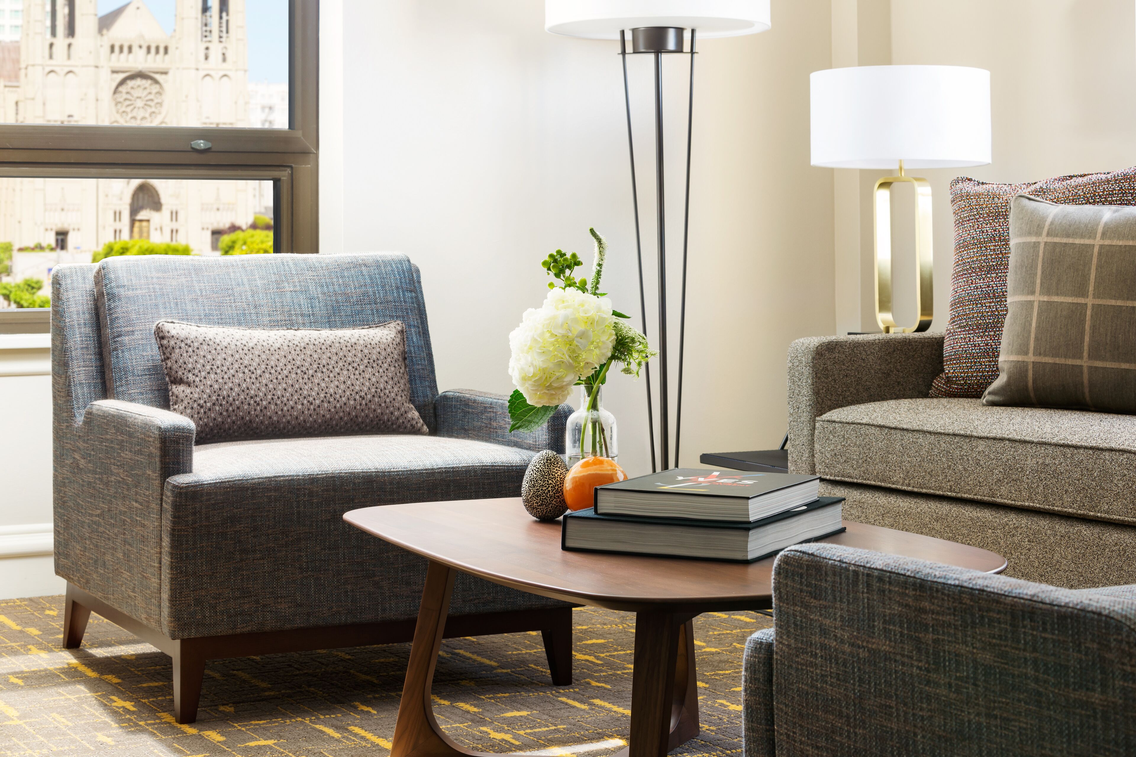 A modern living room with a grey armchair, a sofa, a coffee table, and a floor lamp.