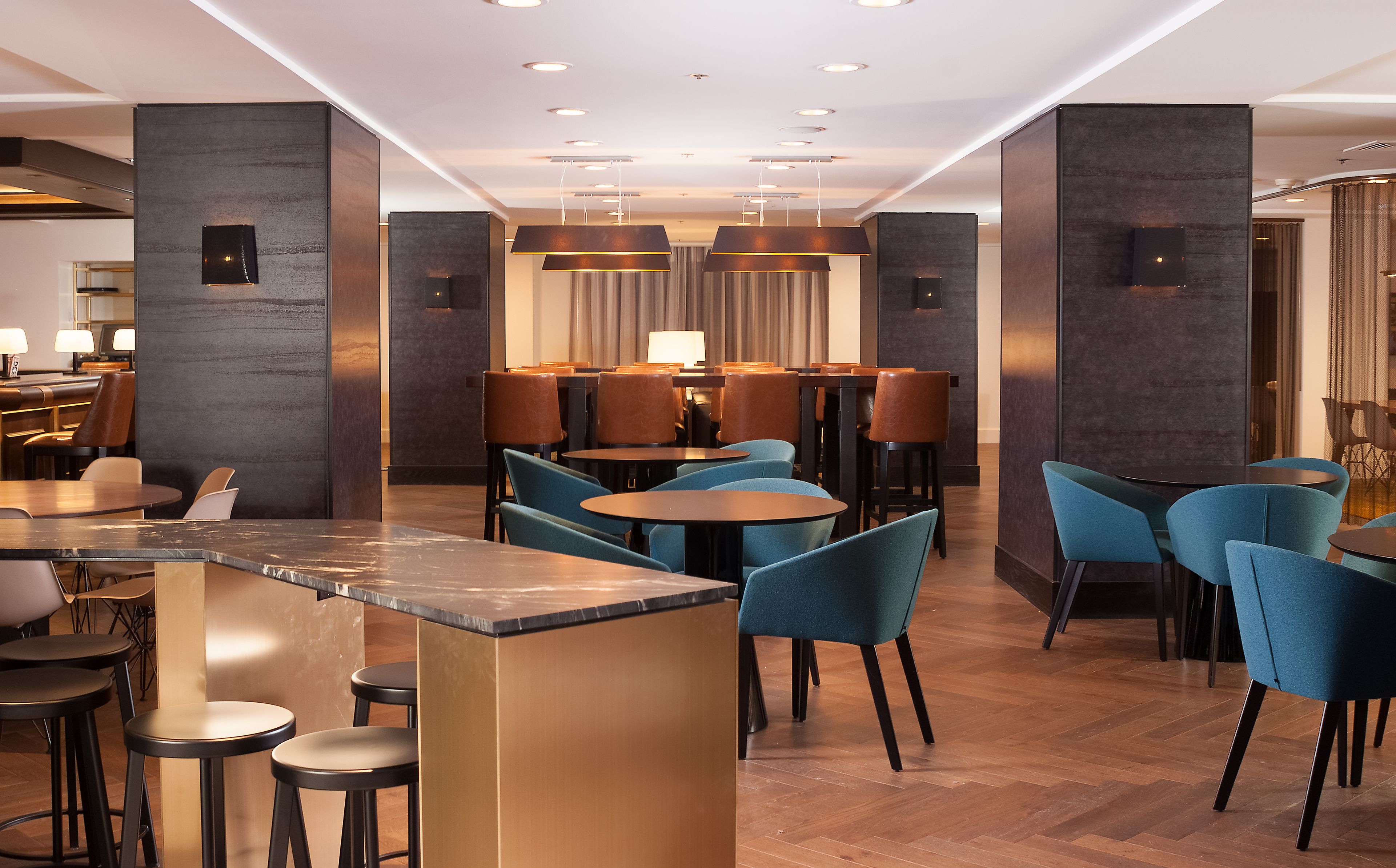 A modern hotel lobby with a bar area, seating arrangements, and a reception desk.