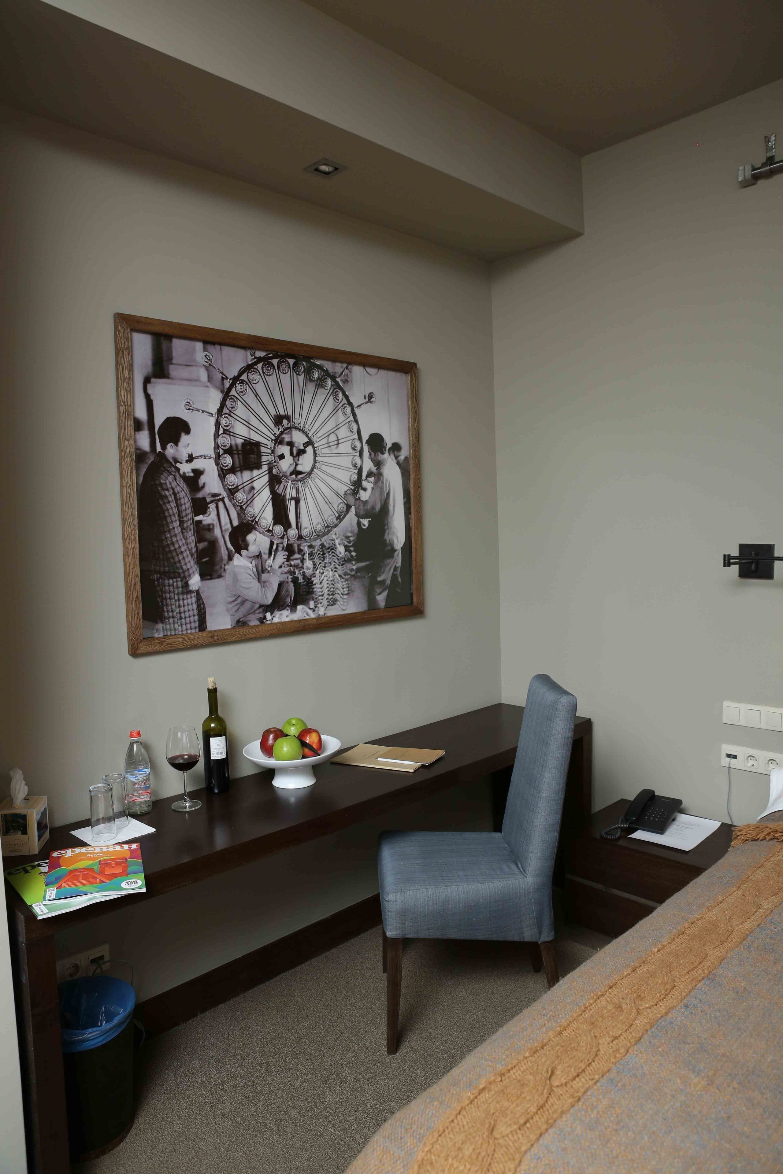 Habitación de hotel con escritorio, silla y una fotografía grande en blanco y negro en la pared.
