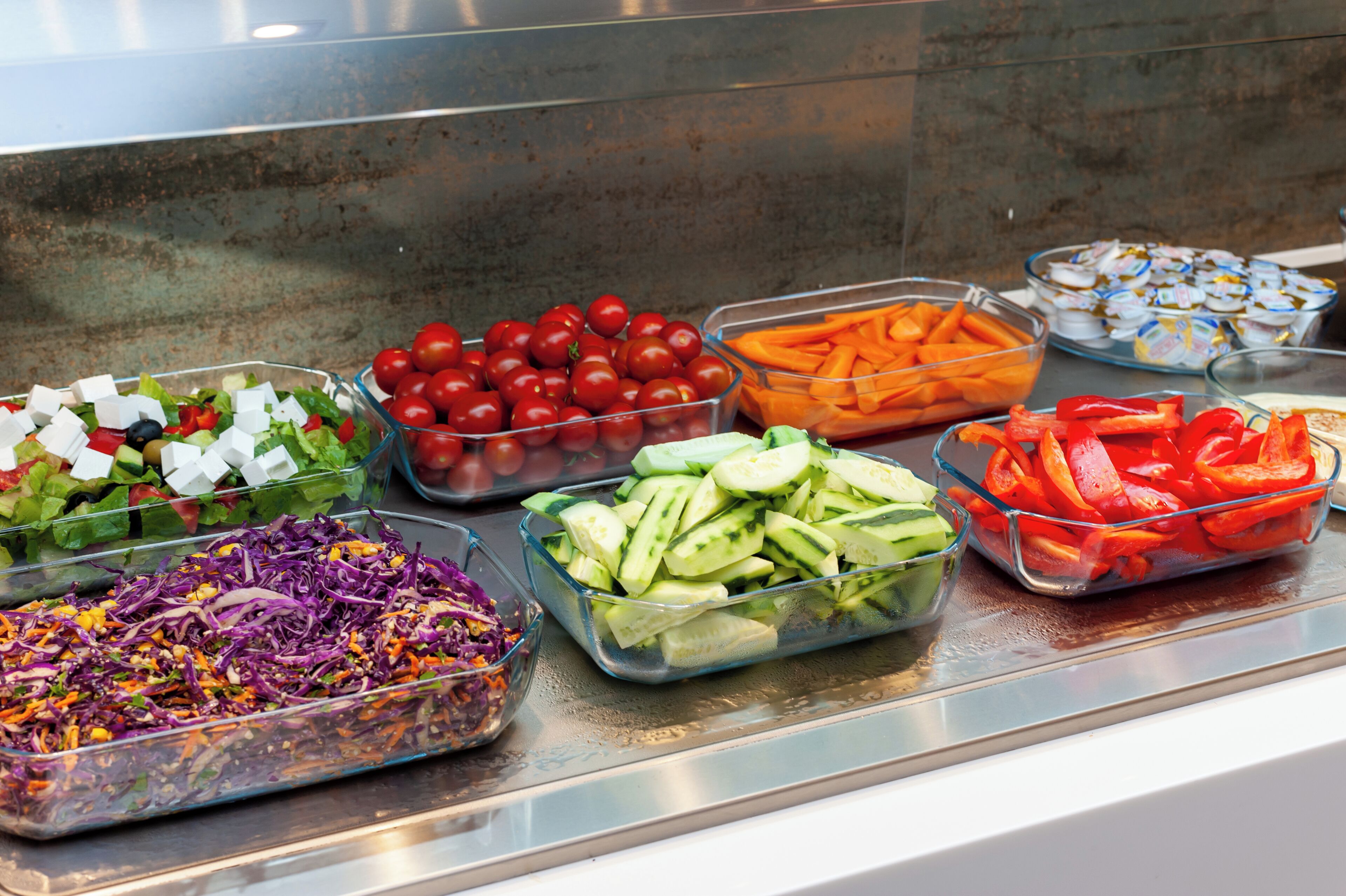 Un bufé con diversas opciones de comida, como ensaladas, frutas y verduras.