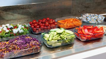 Un bufé con diversas opciones de comida, como ensaladas, frutas y verduras.