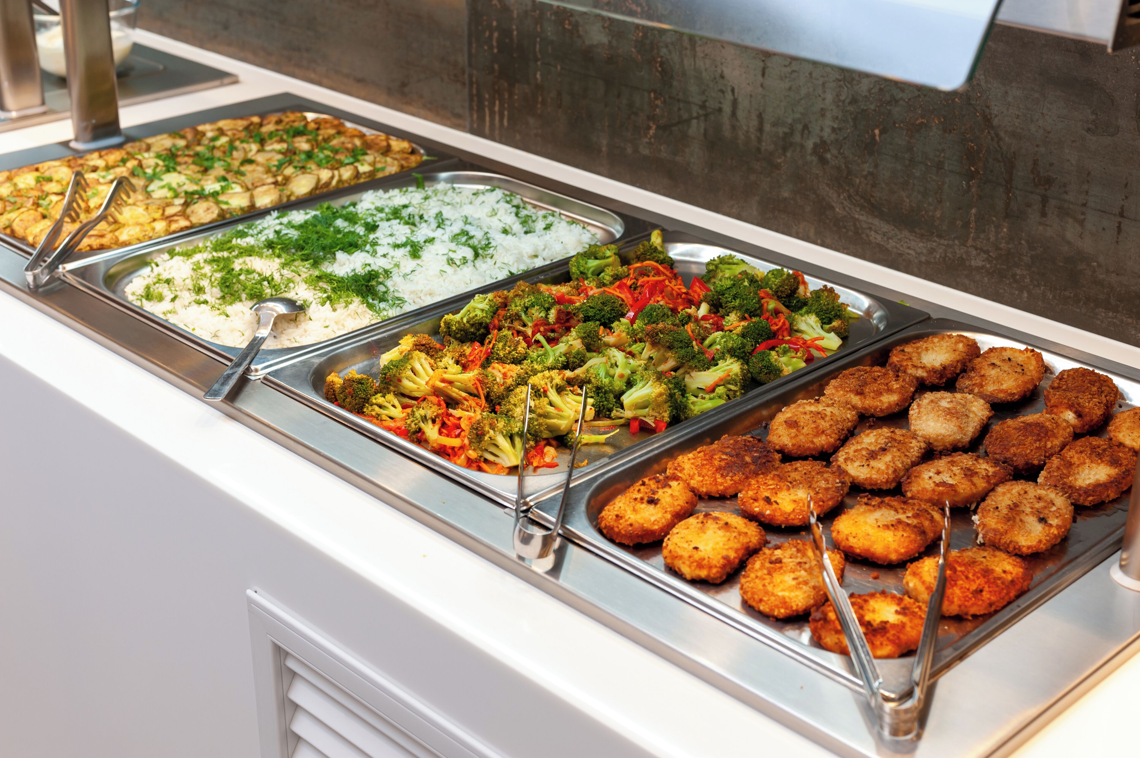 A buffet with various food options including rice, vegetables, and meat dishes.