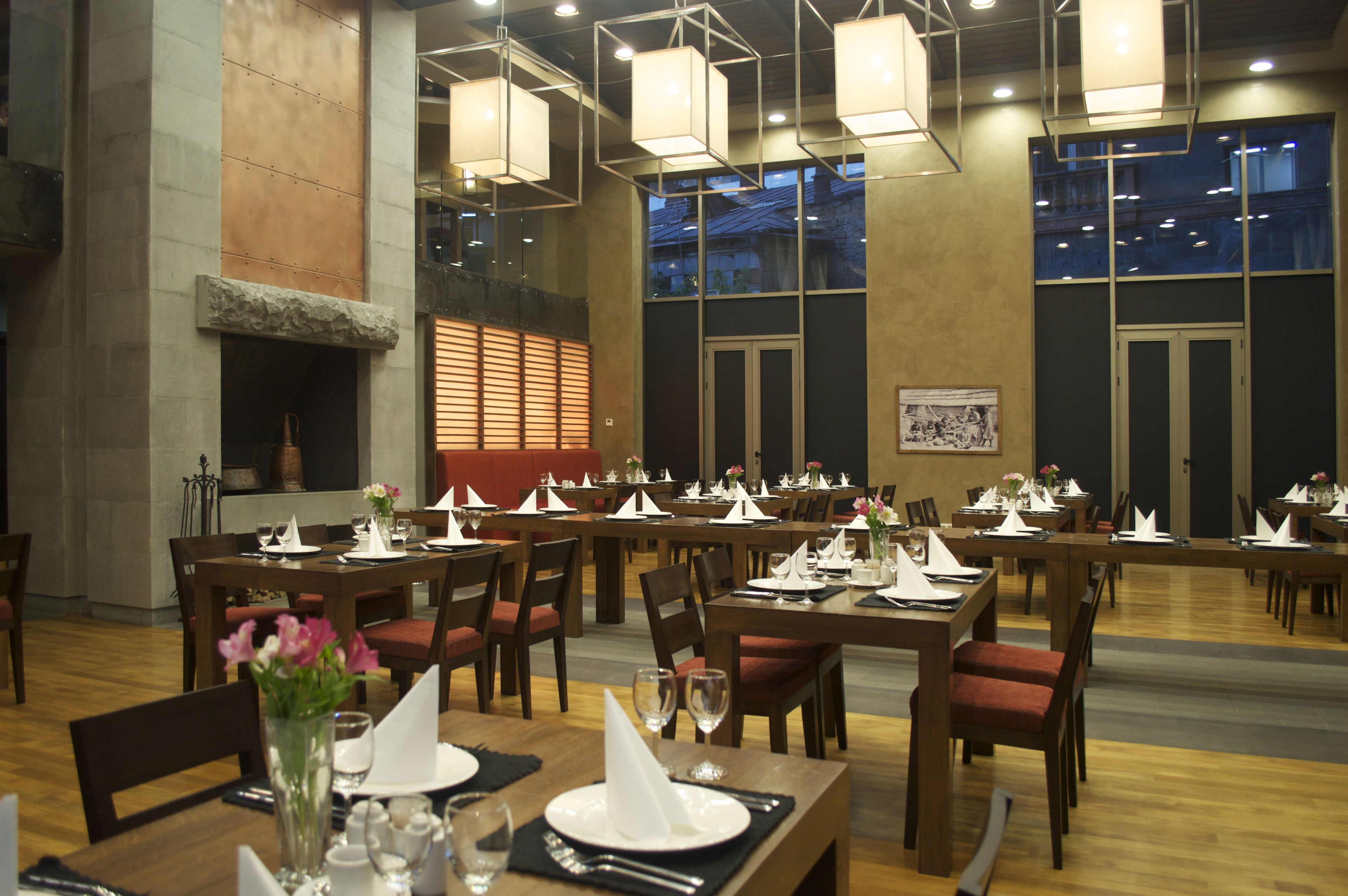 Een restaurant met verschillende tafels gedekt voor diner, houten stoelen en hangende lampen.