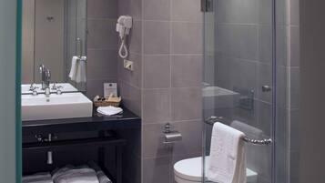 Een moderne badkamer met een douchecabine van glas, een wastafel met spiegel en een toilet.