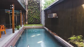 Una piscina con cubierta de madera y pared vertical cubierta de jardín.