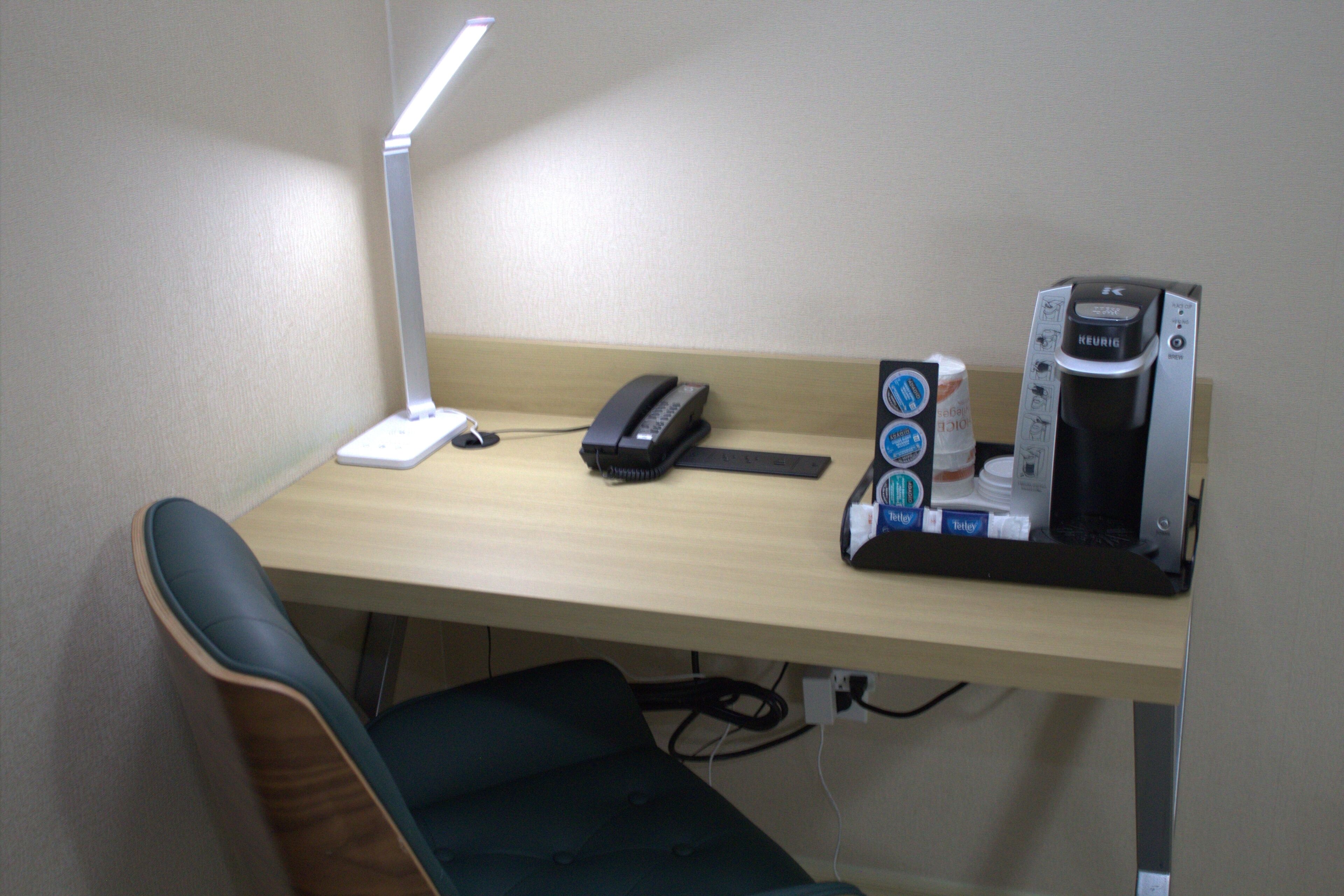 A desk with a lamp, a phone, and a coffee maker.