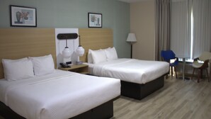 Une chambre d’hôtel avec deux lits, un bureau, une chaise et deux lampes fixées au mur.