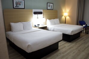 A hotel room with two beds, a nightstand with a phone, a lamp, and a chair. - Quality Inn (Saugeen Shores)