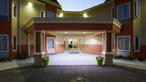 L’entrée d’un hôtel, avec un passage couvert, une porte centrale et deux jardinières.