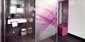 Un baño moderno con cabina de ducha de vidrio, un lavabo blanco y una pared de acento morada.