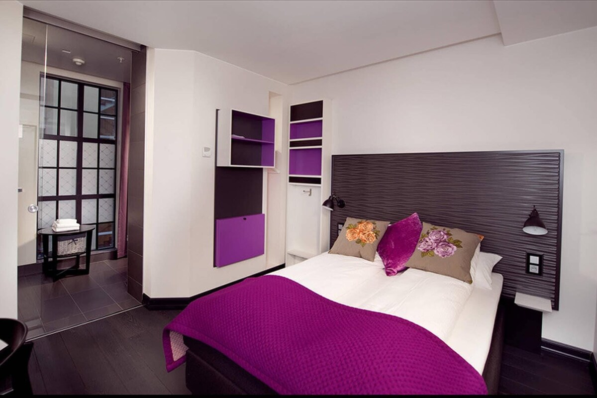 Une chambre moderne avec un grand lit, des étagères intégrées et une vue sur la salle de bain.