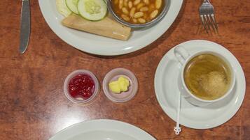 A table with two plates of food, a cup of tea, and condiments.