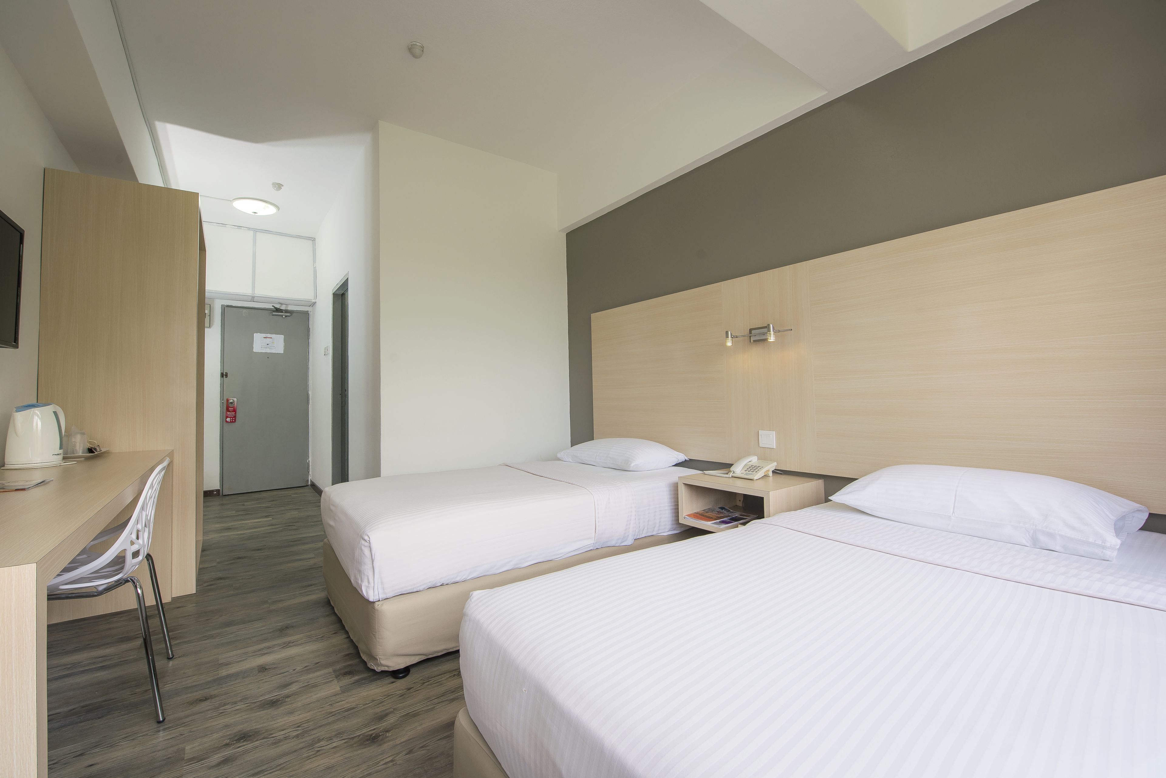 A hotel room with two beds, a desk, and a chair.