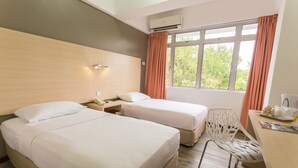 A hotel room with two beds, a desk, a chair, and a window with curtains.