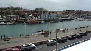 A harbor with boats, a dock, and a road with cars. - The Cavendale (Weymouth)