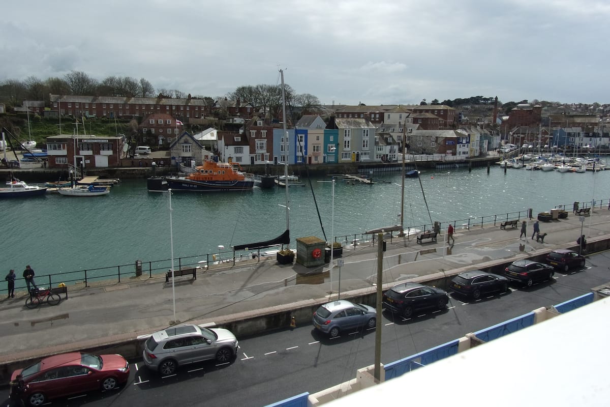 A harbor with boats, a dock, and a road with cars.