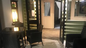 A room with a dining table and chairs, a small kitchen area, and a glass door leading to another room. - The Crown Inn (Rhayader)