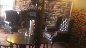 A cozy interior with leather armchairs, a stone wall, and a fireplace. - The Crown Inn (Rhayader)