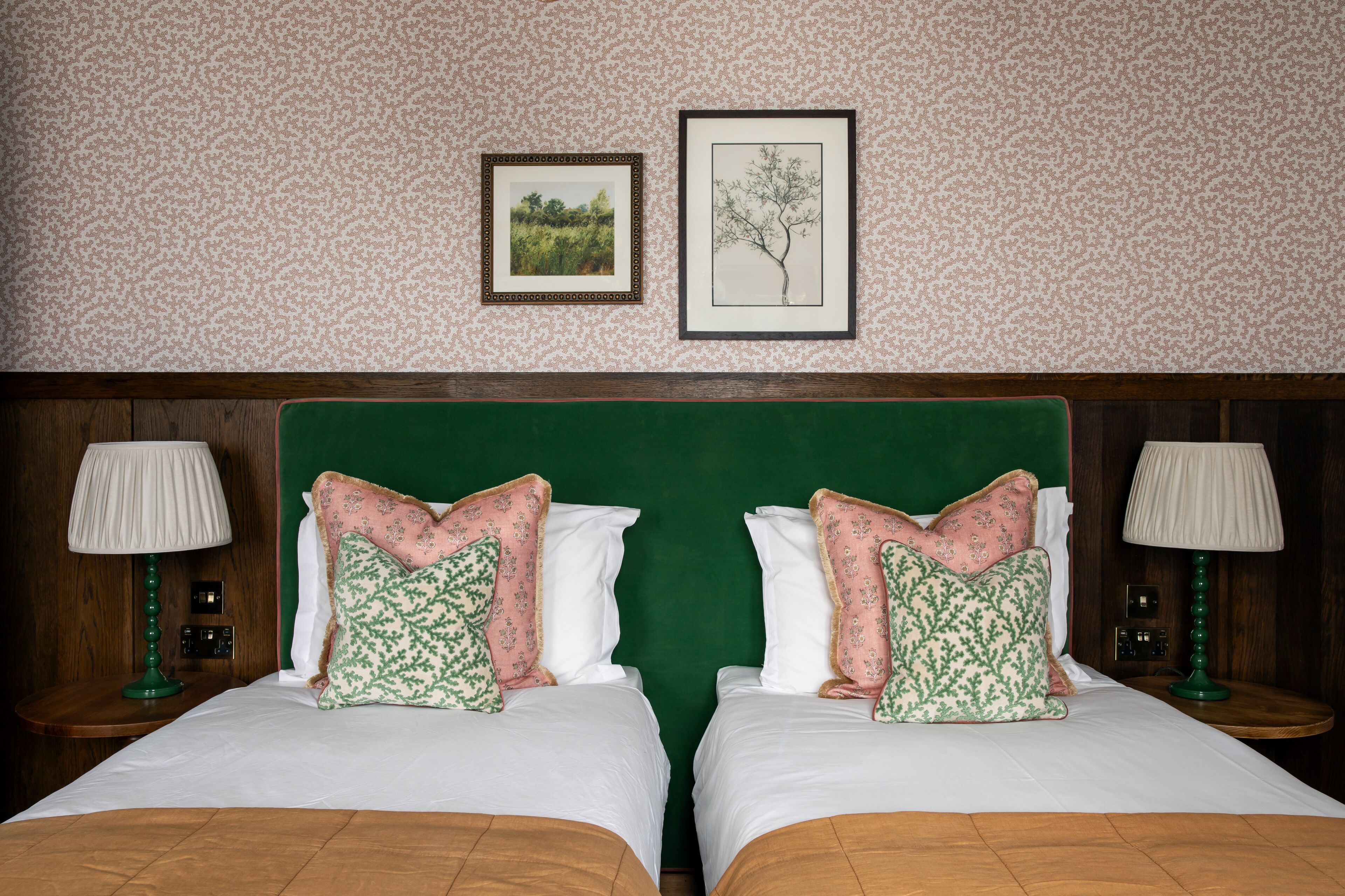 A double bed with green headboard, two pillows, and a framed picture above.