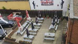 A courtyard with outdoor seating, a mural, and a parked car. - Swan Hotel (Milton Keynes)