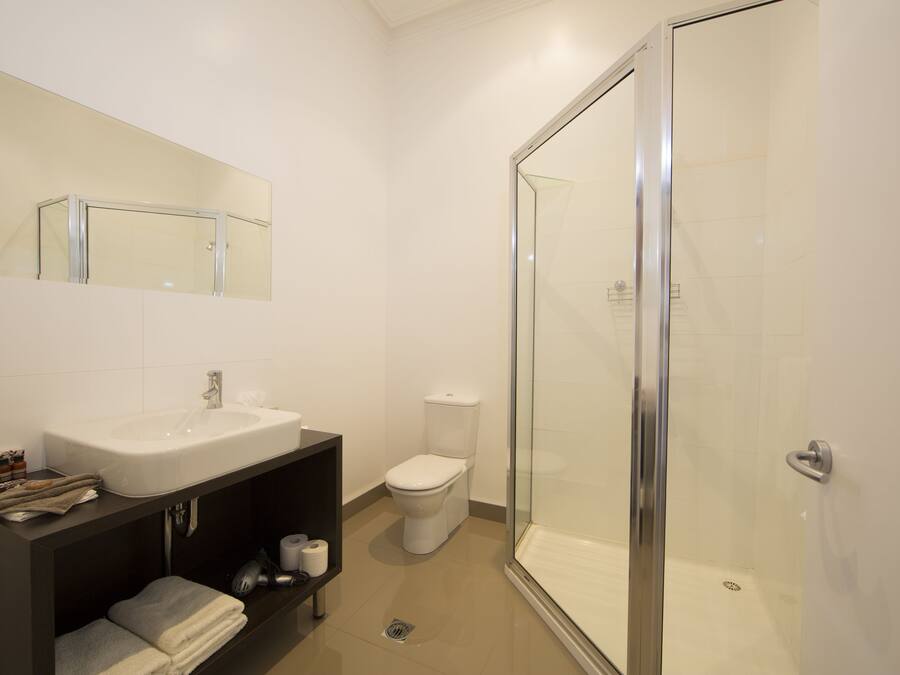 Un baño moderno con cabina de ducha de vidrio, lavamanos blanco y un inodoro.
