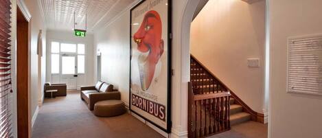 A hallway with a large poster of a red fox, a staircase, and a seating area with a sofa and ottoman.