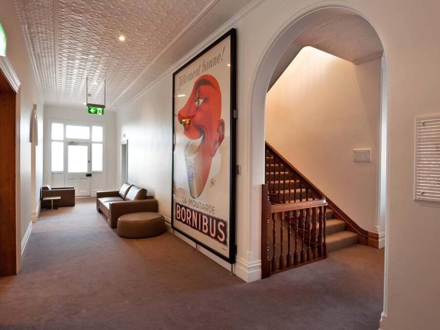 A hallway with a large poster of a red fox, a staircase, and a seating area with a sofa and ottoman.
