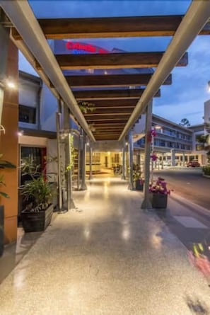 A hotel entrance with a covered walkway, potted plants, and a sign indicating the hotel name.