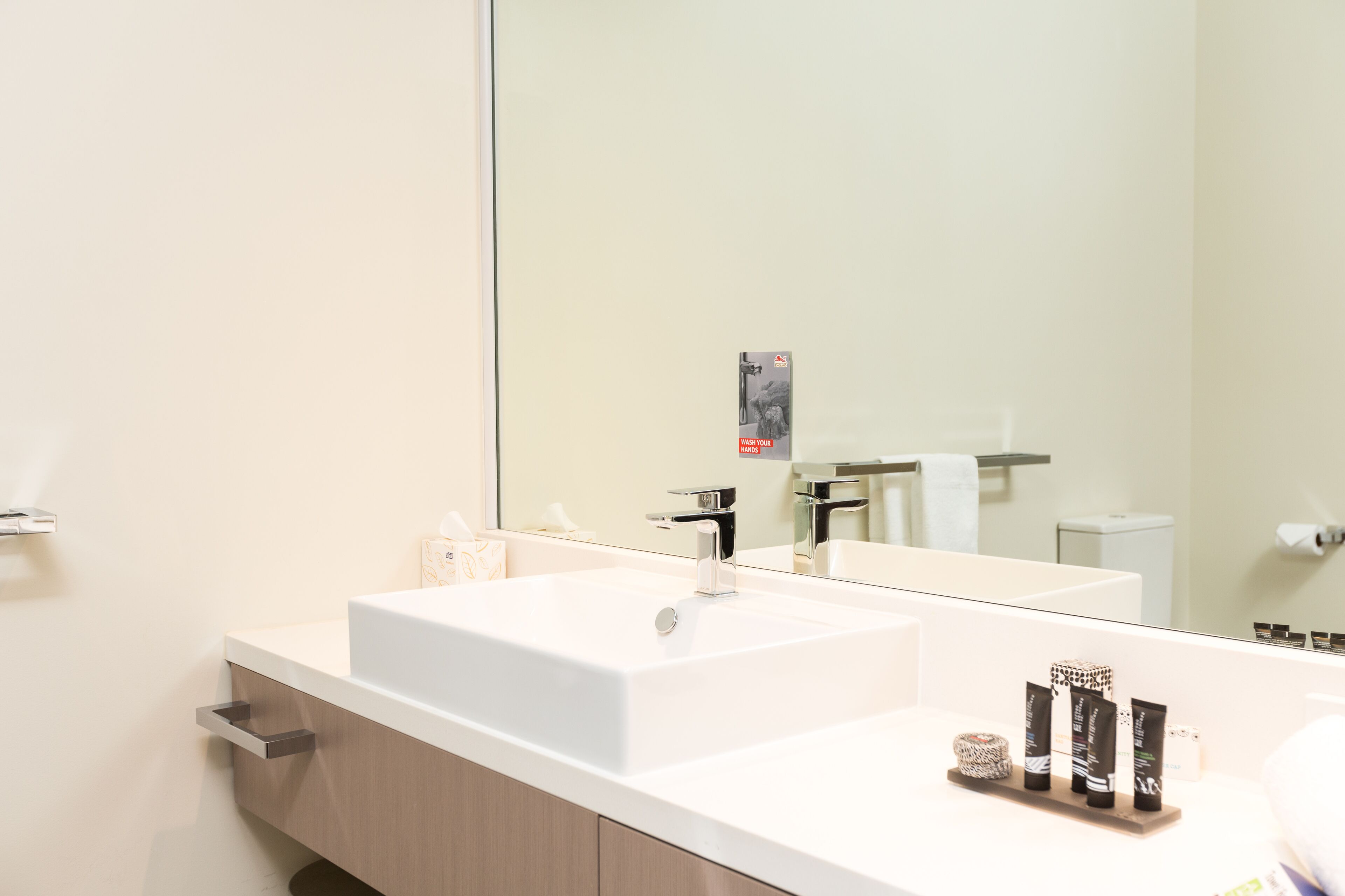 Un baño moderno con un espejo grande, dos lavamanos y un mueble de tocador con un cajón.