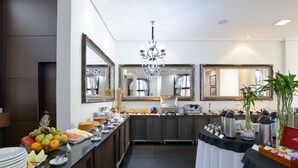 Un espace dédié au petit-déjeuner à l’hôtel, avec un buffet proposant des fruits, des viennoiseries et des machines à café.