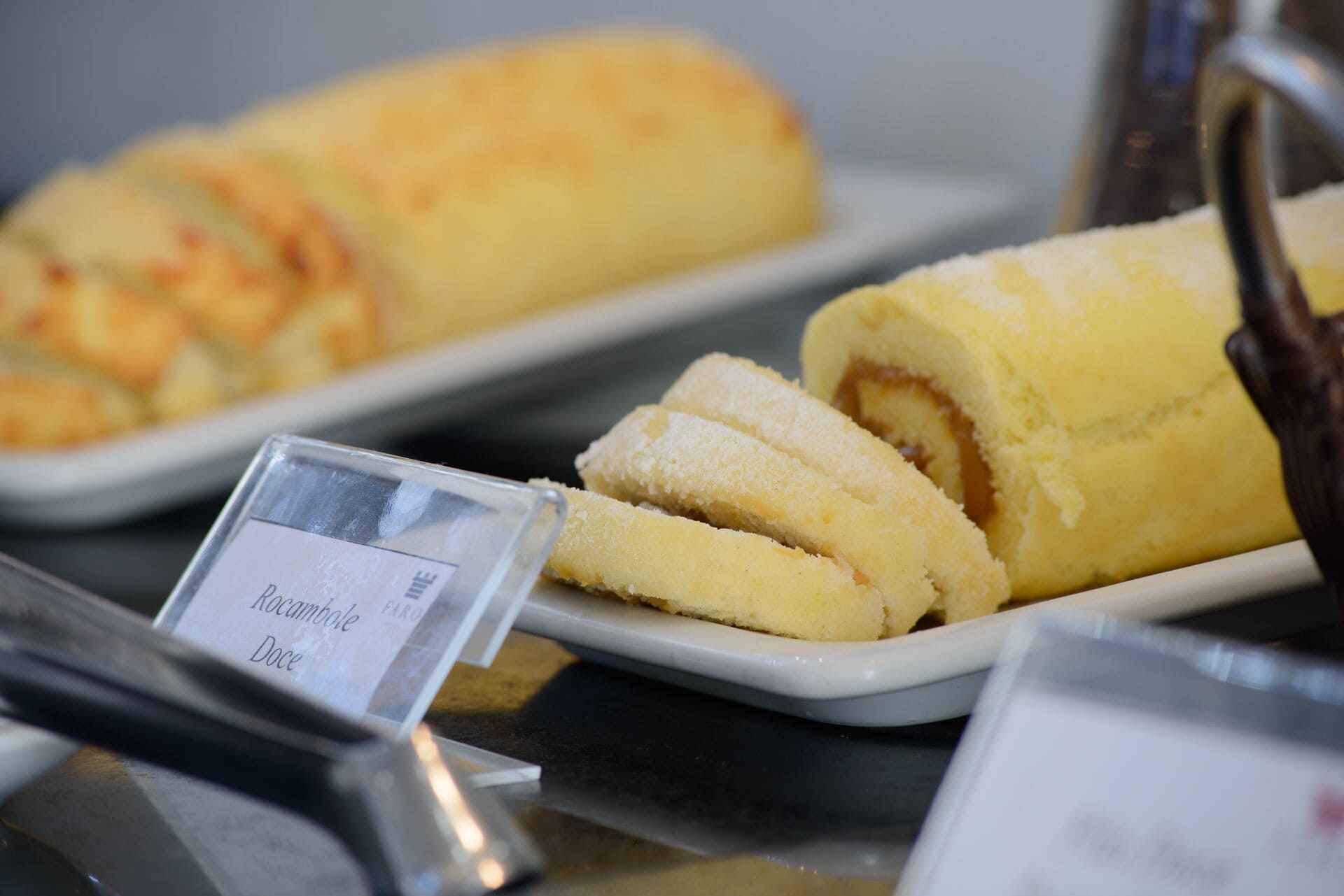 A display of pastries, including a rolled dessert and a slice of cake, on a tray with a sign indicating the price.
