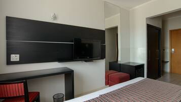Una habitación de hotel moderna con una cama, un escritorio, un televisor y una silla roja.