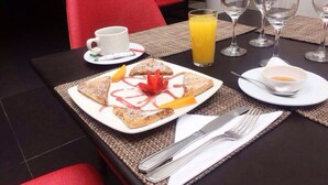 Una escena de desayuno con un plato de pasteles, un vaso de jugo de naranja y una taza de café sobre una mesa.