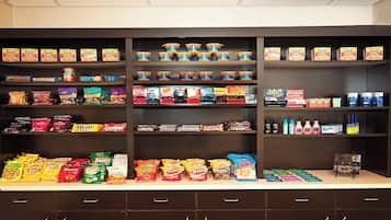 Una exhibición de aperitivos y bebidas en una tienda, con diversos productos en estantes y un mostrador.