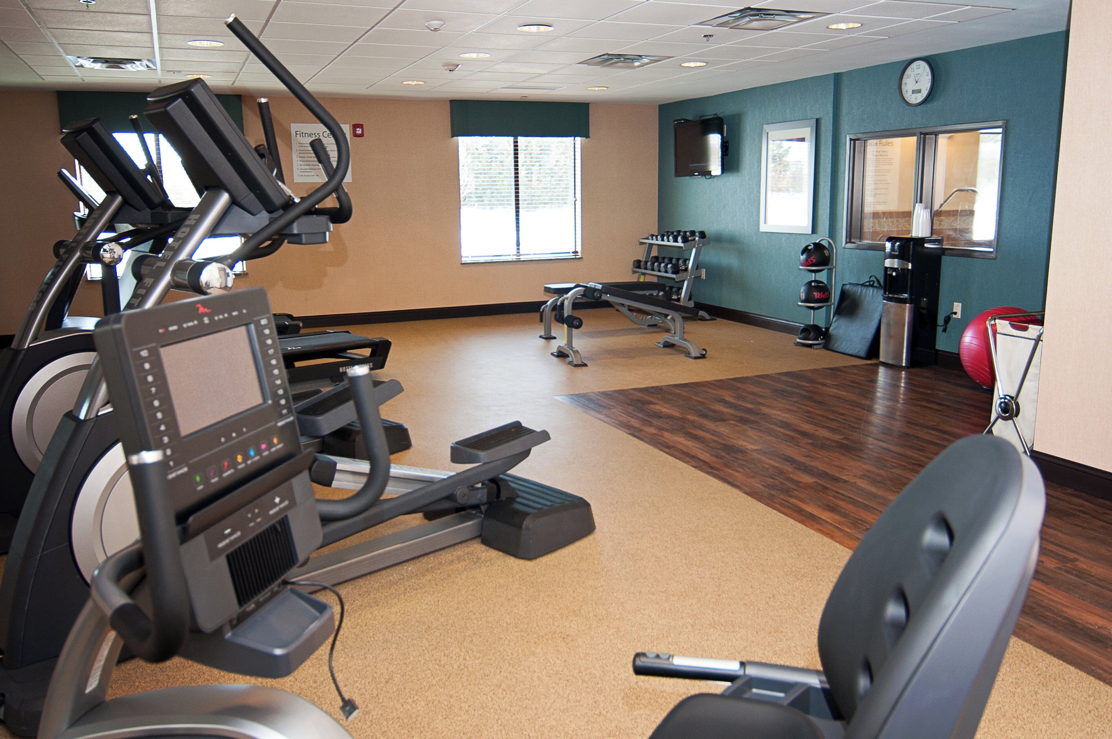 Un gimnasio con equipamiento de ejercicio, una cinta de correr y una bicicleta estática.