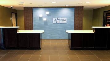 Un área de recepción con dos mostradores, una pared azul con un diseño ondulado y un letrero que dice 'Holiday Inn Express'.