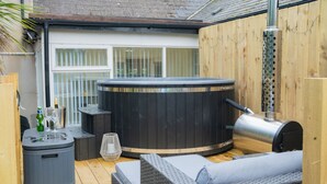 Un jacuzzi, asientos exteriores y una terraza de madera.