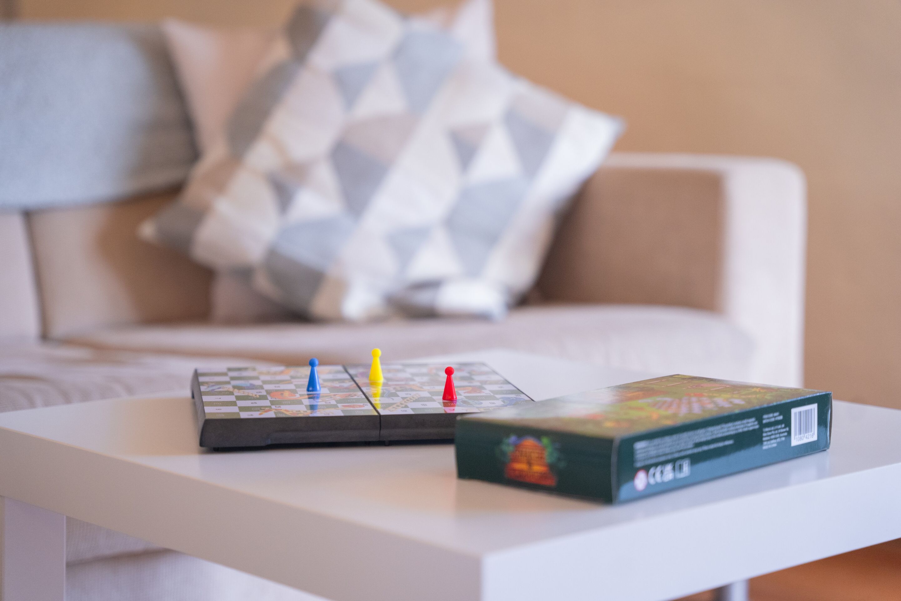 A board game on a white table with a cushion in the background.