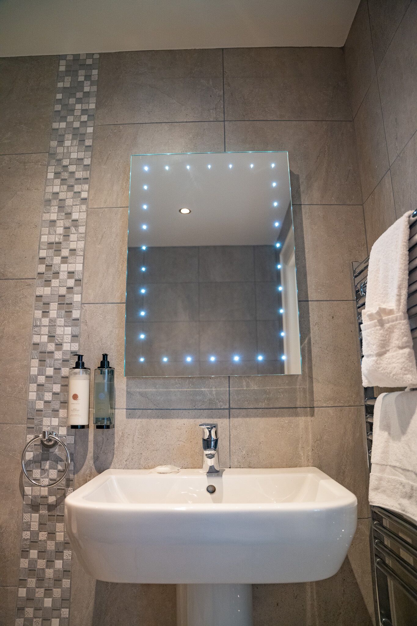 Un baño con un espejo grande, un lavabo y un perchero para toallas.
